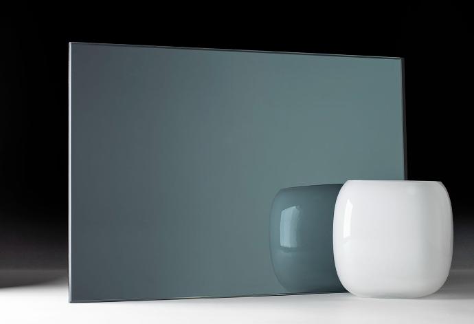 A square piece of greenish-colored mirror and a bowl on a dark background